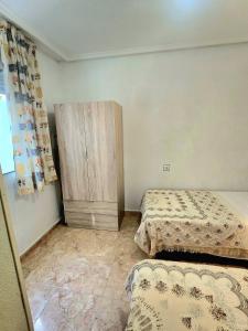 a bedroom with two beds and a wooden cabinet at Bungalow Brisa de Mar in Torrevieja
