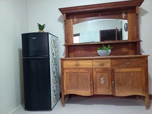 a black refrigerator next to a wooden dresser with a mirror at Bluewater Guesthouse in Port Elizabeth