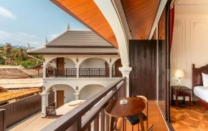 a room with a balcony with a bed and a chair at The Jam Central in Luang Prabang
