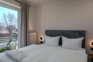 a bedroom with a white bed and a large window at Johouse Zingst Johouse Zimmer 07 in Zingst