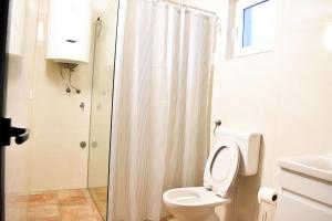 a white bathroom with a toilet and a shower at Konoba Oklop in Tomislavgrad