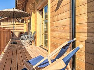 a couple of chairs on a deck with an umbrella at Chalet Nockhütte by Interhome in Hochrindl +13 photos