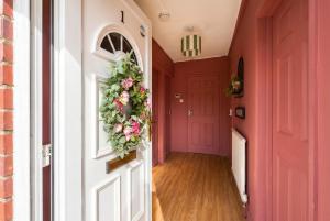 a hallway with pink walls and a door with a wreath at Central Brockenhurst Village Flat with Free Parking in Brockenhurst