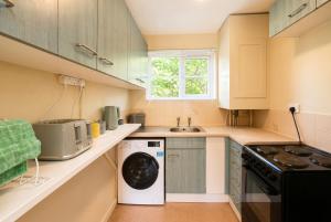 a small kitchen with a washer and dryer in it at Central Brockenhurst Village Flat with Free Parking in Brockenhurst