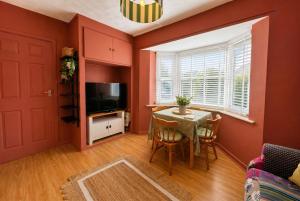 a dining room with red walls and a table and chairs at Central Brockenhurst Village Flat with Free Parking in Brockenhurst