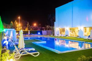 a swimming pool at night with two chairs and an umbrella at Hôtel Tamuda Beach in M'diq