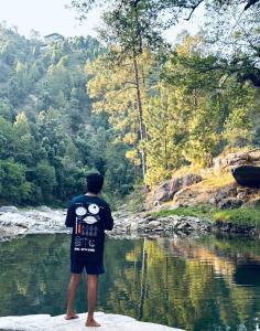 a man standing on a rock looking at a river at Tent-It India Experiences in Mukteshwar