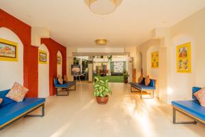 a hospital lobby with blue chairs and a plant at Kyriad Prestige Goa by Mastiff in Calangute +157 photos