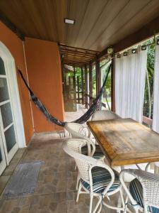 a porch with a hammock and a wooden table and chairs at Villa São Lourenço in Bertioga