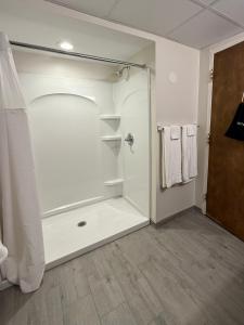 a white bathroom with a shower and towels at Mushroom Cap Motel in Mesick