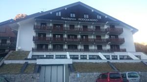 um edifício com um carro vermelho estacionado em frente dele em Rododendro Apartment em Passo San Pellegrino