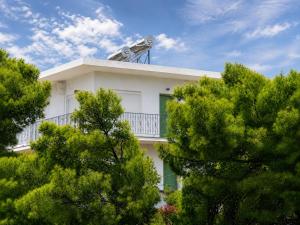 a white house with a balcony and trees at Kalimera Aegina in Agia Marina Aegina