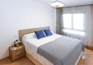 a bedroom with a bed with blue pillows and a window at Los Juncos HomeStay by Turismar in La Pineda +34 photos