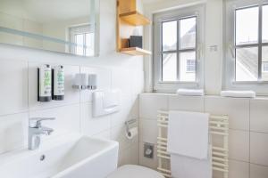 a white bathroom with a sink and a toilet at Boutique-Hotel STRANDHAUS Ahrenshoop in Ahrenshoop +81 photos