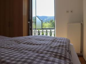 a bed with a checkered blanket in front of a window at Rübenkämpers Ferienwohnungen in Schmallenberg