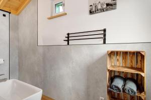 a bathroom with a sink and a shelf with towels at Tiny Haus 2 - Feige in Kressbronn am Bodensee +21 photos
