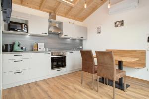 a kitchen with white cabinets and a table and chairs at Tiny Haus 2 - Feige in Kressbronn am Bodensee