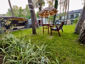 a picnic table and a chair under an umbrella in a yard at Dębowy zakątek camping in Pobierowo