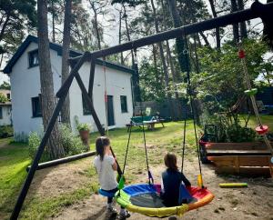 two girls playing on a swing set in a yard at Dębowy zakątek camping in Pobierowo