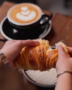 Eine Person, die ein Croissant und eine Tasse Kaffee hält. in der Unterkunft Bed&Harmony in Colleferro