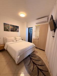 a bedroom with a white bed and a television at ARAD-DEAD SEA BASHIRIS PLACE in Arad