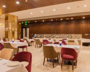a dining room with white tables and red chairs at Royal Crown Muscat in Muscat
