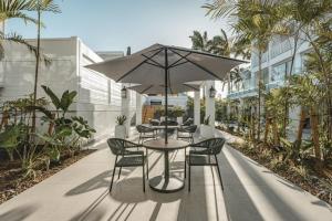 a patio with tables and chairs and an umbrella at Fort George Hotel and Spa in Belize City