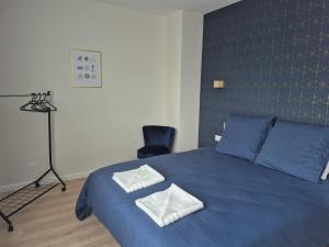 a bedroom with a blue bed with two towels on it at Doré in Carhaix-Plouguer