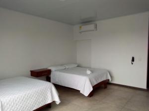 two beds in a room with white walls at Hotel Nayarith in Acacías