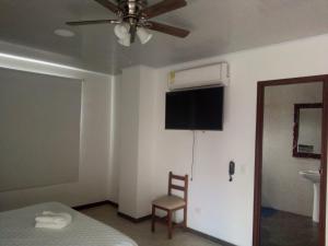 a bedroom with a bed and a fan and a chair at Hotel Nayarith in Acacías