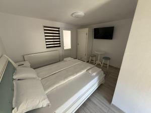 a white bedroom with a bed and a window at Lucatony's Guesthouse in Cîmpeni +6 photos