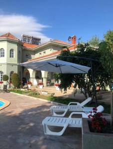 a group of white chairs and an umbrella in front of a house at SUNNY HOUSE APARTMENTS WITH an OUTDOOR POOL AND FREE PARKING in Skopje