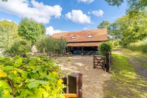 a barn with a fence and trees in front of it at The Roost in Wendling