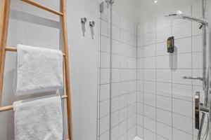 a bathroom with a shower with white tiles at Nena Apartments Bremen by LESA in Bremen +30 photos