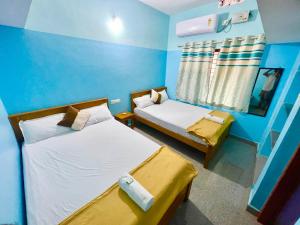 two beds in a room with blue walls at R J Homestay in Māvalli
