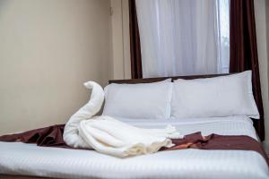 a bed with white sheets and white pillows and a window at ST Augustine Hotel Ltd in Kisumu +3 photos