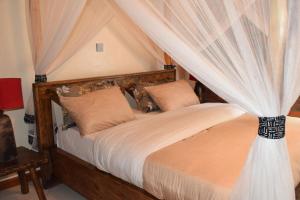 a bedroom with a canopy bed with curtains at Mrëmbo Boutik Hôtel in Ruhengeri