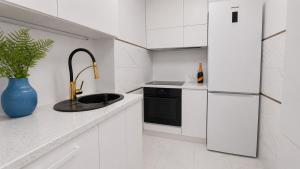 a white kitchen with a sink and a refrigerator at Albatros Apartment Stogi in Gdańsk +3 photos
