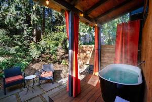 a tub on a deck with a table and a chair at Artbliss Hotel in Stevenson
