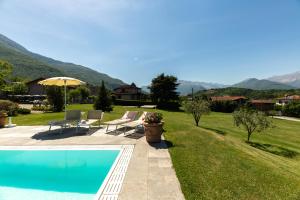a swimming pool in a yard with chairs and an umbrella at Foresteria Villa Margherita in Colico +40 photos
