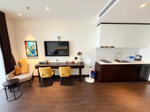 a kitchen with a table and yellow chairs and a counter at Sapphire Hạ Long Luxury Studio in Ha Long