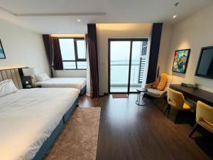 a hotel room with two beds and a desk at Sapphire Hạ Long Luxury Studio in Ha Long