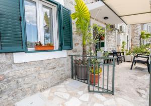 a patio of a house with green windows and plants at Seafront Stone House Maxim in Tivat