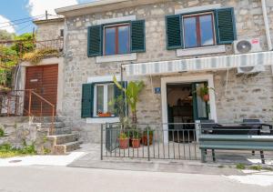 a building with green windows and a bench in front of it at Seafront Stone House Maxim in Tivat