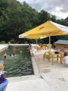 a pool with a yellow umbrella and people in the water at Dogurashi Turbaza in Tsʼageri