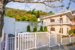 a white picket fence in front of a house at Adviga by The StayCationer in Dehradun