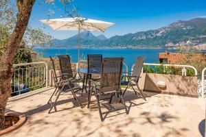 a patio with a table and chairs and an umbrella at Villa Incanto Adults Only in Brenzone sul Garda