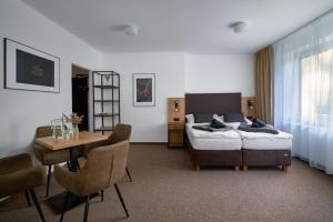 a hotel room with a bed and a table and chairs at Hotel Popel in Stachy