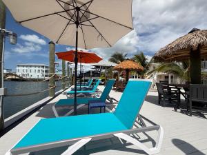 a row of blue chairs and an umbrella on a deck at Manatee Bay Inn in Fort Myers Beach