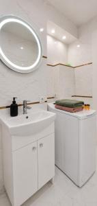 a white bathroom with a sink and a mirror at Albatros Apartment Stogi in Gdańsk